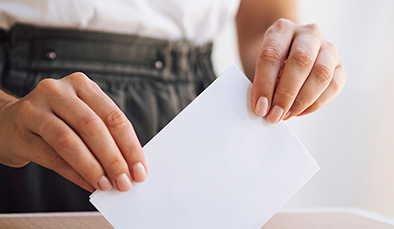 woman placing ballot box 394x229
